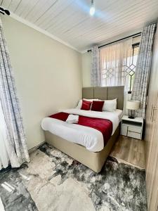 基苏木Elma Executive Suites - Milimani Kisumu, 3 BDR的一间卧室配有一张带红色枕头的大床