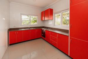 塔科拉迪Luxurious Estate的红色的厨房,配有白色的墙壁和红色的橱柜