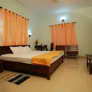 提喀迪Pknhomestay kumily thekkady的一间卧室配有带橙色窗帘的大床