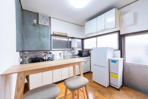 东京GuestHouse　YOU&I平和島的厨房配有白色橱柜和带2张凳子的台面