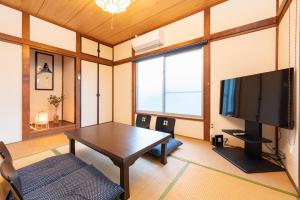 东京GuestHouse　YOU&I平和島的客厅配有桌子和平面电视。