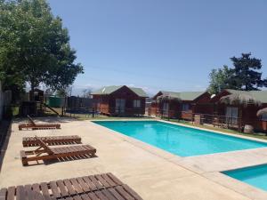 利马切Cabañas Marlen的房屋旁的游泳池配有躺椅和椅子