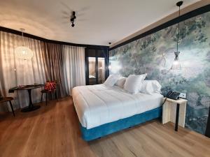 塞雷纳新镇Hotel Suites Moma Centro的卧室配有一张白色大床,墙上挂有绘画作品