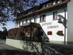 于林根-比肯多夫Gasthaus zum Schwanen的白色的建筑,花朵在建筑的一侧