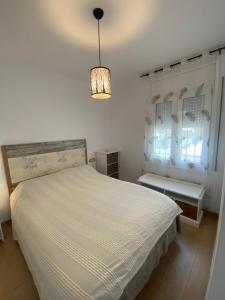 兰卡El Mirador de Llançà的卧室配有白色的床和吊灯。