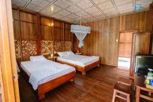 Ấp Nhơn BìnhMuong Dinh Lodge的配有木墙和电视的客房内的两张床