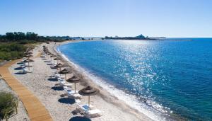 普拉Golf & Sea Residence Is Molas的海滩上设有遮阳伞和椅子,还有水