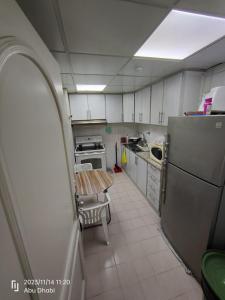 阿布扎比Bedroom 4的一间带桌子和冰箱的小厨房