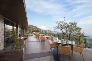 穆索里Fortune Resort Grace, Mussoorie - Member ITC's Hotel Group的阳台餐厅,配有桌椅