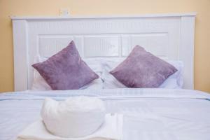 马查科斯Elnara Suites的白色的床、紫色枕头和白色床头板