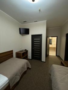 波尔塔瓦Status Hotel的一间卧室设有两张床,墙上配有电视。