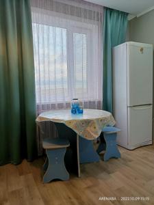 巴甫洛达尔1 комнатная квартира в Павлодаре的厨房配有一张桌子和白色冰箱