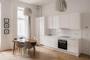 维也纳HeyMi Apartments Zentagasse的厨房配有白色橱柜和桌椅