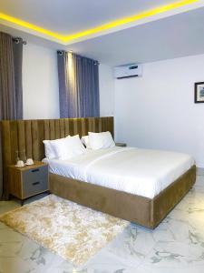 阿布贾Omah Apartments的一间卧室配有一张大床和木制床头板