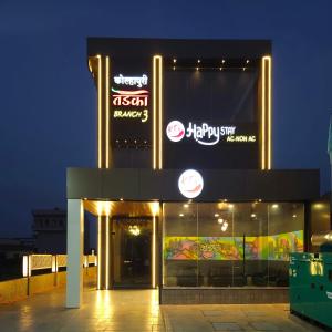 戈尔哈布尔Hotel Happy Stay Kolhapur 2 km from kolhapur airport的一座建筑物,晚上有标志