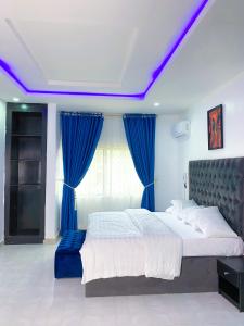 阿布贾D & D Apartments的一间卧室配有一张带蓝色窗帘的大床