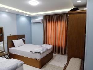开罗The perfect stay in Cairo al muhandesin Nile luxury apartment的一间卧室配有两张床和橙色窗帘