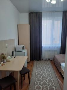 塔尔迪库尔干Апарт отель Welcome的小房间设有一张床、一张桌子和一张桌子