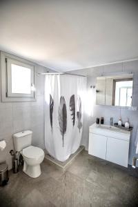 埃尔莫波利斯Seaside Serenade 1, suite的浴室设有卫生间和带羽毛的浴帘。