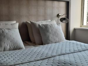 于尔克Bij de Haven op Urk的一张带白色枕头的床和一盏灯