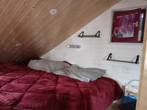 Ménétrux-en-JouxLa p'tite maison bois du hérisson的一间卧室配有一张红色棉被的床