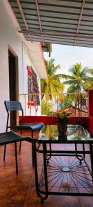 瓦加托Mitra Hostel (By The Pool)的一间设有桌子和椅子的客房,并种植了棕榈树