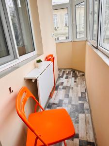 布加勒斯特Euro Apartment的一个小房间,设有窗户,配有一张橙色椅子