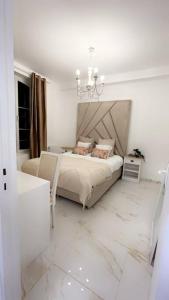 德勒Golden House的白色卧室配有一张床和一个吊灯