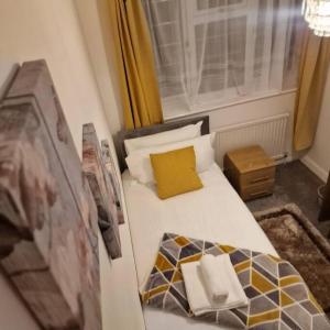 Wanstead5 Bedroom Luxury Home with Garden in East London的小卧室配有一张带黄色枕头的床