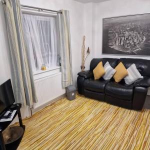 Wanstead5 Bedroom Luxury Home with Garden in East London的客厅配有带黄色枕头的黑色皮沙发