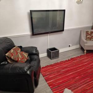 Wanstead5 Bedroom Luxury Home with Garden in East London的客厅配有黑色真皮沙发和平面电视。