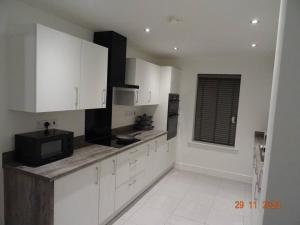 Cross GatesBeautiful 4 bed house in Leeds的厨房配有白色橱柜和黑微波炉