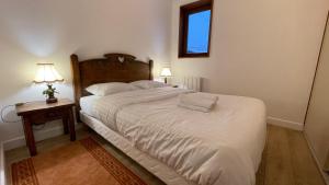 梅杰夫Les Comtes de Savoie - Appartement rénové proche du centre de Megève avec vue sur le Mont d'Arbois的卧室配有一张白色的大床和床头柜。