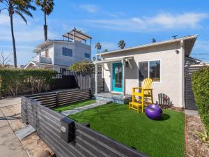 圣地亚哥Classic Beach Bungalow - Parking, Private Patio & Pet Friendly!的一座房子,有一个院子,有一个紫色的球和一个黄色的椅子
