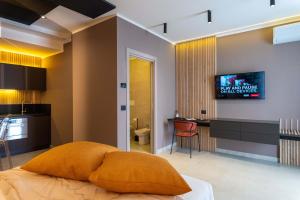 多索博诺La Pergola Suites的一间卧室配有一张床、一张书桌和一台电视