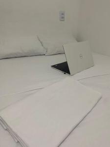 特赖里Pousada manu的一张白色床顶上的笔记本电脑