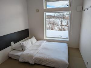 二世古乌诺宾馆的卧室配有白色的床和窗户。