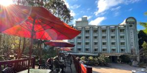 鹿谷乡孟宗山庄大饭店的一座配有红色雨伞和桌椅的建筑