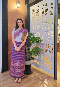 Ban Don Klangโรงแรมเรือนไทย 1 (Thai Guest House)的站在植物旁边的身着紫色衣服的女人