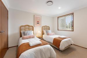 蚬壳港Shell Cove Coastal Haven的一间卧室设有两张床和窗户。