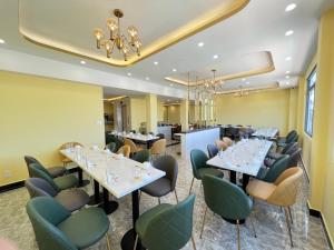 大叻Thanh Thanh Hotel的餐厅设有白色的桌子和绿色的椅子