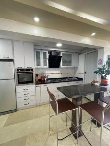 Catia La MarComodo Apartamento frente al Aeropuerto Maiquetia的厨房配有白色橱柜和桌椅