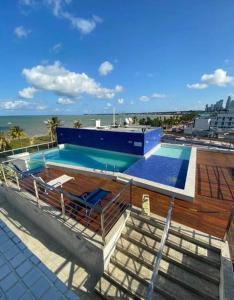 若昂佩索阿Flat - solar do atlântico的一座游泳池,位于一座毗邻大海的建筑的顶部