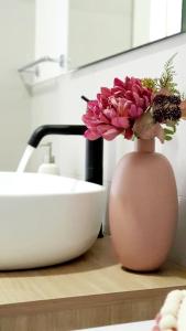 里乔内Appartamento Garden的水槽旁的柜台上花的粉红色花瓶