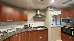 伊斯兰堡Centaurus Apartment City View Three Beds的厨房配有木制橱柜和炉灶烤箱。