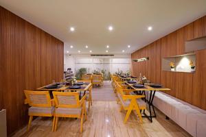 班加罗尔Nest By Rivido Apart Hotel, Bannerghatta road的餐厅拥有木墙和桌椅