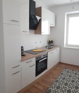 维也纳新城Top Appartement für Business-Wohnen-Urlaub的厨房配有白色橱柜、水槽和炉灶。
