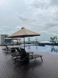 巴淡岛中心Wawa Guesthouse Pollux Habibie Batam Tower A 18的游泳池畔的2把躺椅和遮阳伞