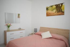 卡利亚里La Casa del Carrubo的卧室配有粉红色的床和梳妆台。