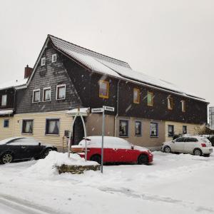 巴特哈尔茨堡Gästehaus Familie Rinke的雪中停放一辆红色汽车的房子